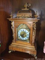 Front view of entire clock in shelf setting showing case, dial and feet