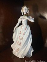 Front angle showing the Victorian style porcelain figurine with white and pink-red gown holding flowers.