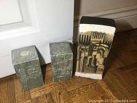 Photo showing two hand carved vintage indigenous stone doorstops and one painted carved brick block.