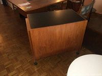 Diagonal front view of teak bar cart with black laminate top closed