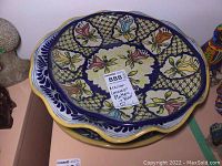 Stacked view showing two platters with colorful Talavera floral designs and scalloped edges