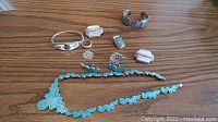 Full assortment of Mexican silver jewelry laid out on a wooden surface, including necklace, earrings, bracelets, rings, and chain.