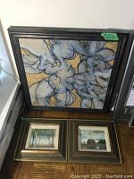 Three framed paintings displayed together: one large abstract and two small landscapes