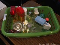 Green plastic basket holding 12 assorted perfume bottles viewed from front