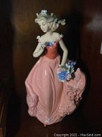 Full view of taller Sorelle figurine wearing coral-pink dress and flower accents