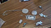 All sterling silver brooches, earrings, pendant, and chain laid out on wooden surface.