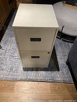 Photo of the top view showing the two-drawer beige metal filing cabinet with black handles.