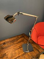 Chrome adjustable dual‐arm desk lamp on wooden surface