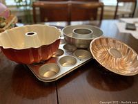 Photo showing ceramic Bundt pan, metal angel food cake pan, muffin tray, and small fluted pan together