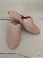 Pair of pink leather slip-on shoes positioned side by side, showing upper leather and toe area.