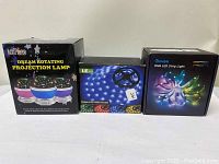 Photo showing the three boxes of the items. On the left, LetsGo Dream Rotating Projection Lamp box, in the middle LE Ruban LED RGB Flexible strip light box, and on the right Govee RGB LED Strip Light box.