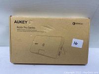 Photo of Aukey Basix Pro Series wireless charging power bank in its packaging box. Box is beige with product image and details.