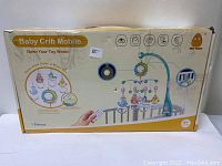 Front side of the boxed baby crib music mobile showing brand, age recommendation, and remote control image.