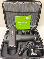 Black massage gun with attachments inside black carrying case with user manual and charger cord.
