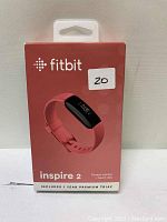 Photo of Fitbit Inspire 2 fitness tracker in original retail box showing pink band and device screen display.