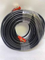 Photo of coiled black outdoor Cat 7 Ethernet cable, approximately 20 meters long, showing one end with red RJ45 connector.