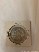 Front side of 1958 Canadian silver 50 cent coin showing the coat of arms with detailed heraldic symbols.