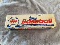 Box labeled '1989 Topps Baseball The Complete Set - 792 Picture Cards' placed on a gray fleece cloth.