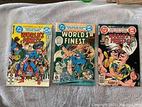 Front covers of three Worlds Finest comic books featuring Superman and Batman.