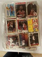 Photo showing a sheet with 12 Michael Jordan basketball cards in protective sleeves with varied card designs mostly action shots of Jordan wearing his Chicago Bulls jersey.