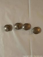 Photo showing four Buffalo head nickel buttons in a row, highlighting their similar size and design.