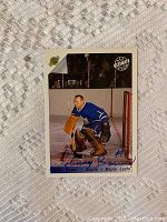 Front of the hockey card showing Johnny Bower in goalie gear for the Maple Leafs, featuring his autograph.