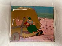 Photo showing front of animation cel artwork featuring the man in green pulling a cart with Pink Panther character.