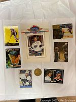 Front view showing six Wayne Gretzky hockey cards arranged around a gold-tone coin on white background
