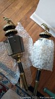 Pair of two ornate antique-style carriage lanterns on wooden floor with bubble wrap, showing overall condition and eagle finials on top