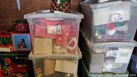 Plastic storage bins filled with Christmas decorations, wreaths, and tree accessories