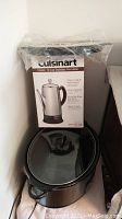 Cuisinart Classic 12-cup stainless steel percolator in box on top of a black Crock Pot slow cooker with glass lid
