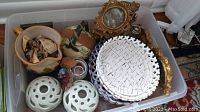Top view of bin containing all lot items: decorative ceramic plates, gilded picture frames, vases, candle holders, jug, tea pot.