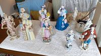 Group view of all Avon Mrs. Albee figurines and display items on a white towel, showing eleven pieces including women figurines, a male figurine, a statue, and a display plaque.