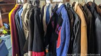 View of multiple jackets and coats on a rack showing variety of colors and materials including suede and leather