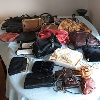 Wide-angle view showing various ladies' purses, clutches, and handbags in different colors and materials arranged on a light blue surface.