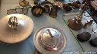 Overview of several metal serving pieces including lidded metal dish, metal cups, and small containers.