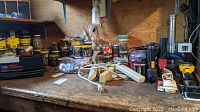 Workbench surface with various hardware items, cans of nails, and scattered tools including extension cords and small parts.