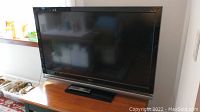 Sony Bravia 52-inch television on wooden surface with remote control in front.