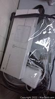 Photo shows white Apple power adapter partially coiled cable with original packaging box inside a plastic bag.