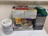 Wide view of the lot showing Maxell DVD+R discs on the left, Kodak CD-R Gold discs in the center, cassette tapes on top, and stacks of CD jewel cases on the right.