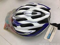 Top view of white and blue Bike Ironman helmet with ventilation slots and attached strap.
