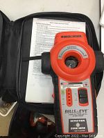 Photo of the Black & Decker Bullseye Laser Level device placed inside an open black soft carrying case, showing device front with detection zone panel and brand label.