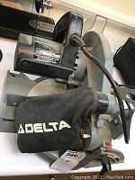 Delta 36-040 mitre saw showing dust collection bag and motor housing with power cord coiled on the saw base.