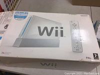 Photo of the original white Nintendo Wii console box showing console and remote images with 'Wii' brand mark visible.