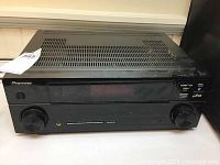 Front view of the black Pioneer audio/video multi-channel receiver showing the display panel, control knobs, and input jack.