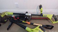 Gardena hedge trimmer with Ryobi edge trimmer and weed puller on floor, view of handles and blades.