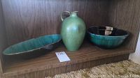 Three Blue Mountain Pottery pieces together on a wooden shelf: round bowl, vase, and oval dish