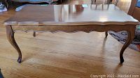 Full view of vintage wooden coffee table showing top surface, scalloped sides and four cabriole legs.