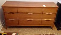 Front view of nine-drawer wood dresser with integrated handles and tapered legs