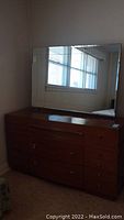 Full view of dresser with attached large mirror reflecting window